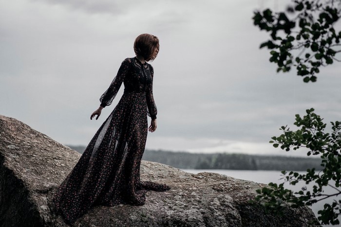 Woman in a floral dress on a rock by the water