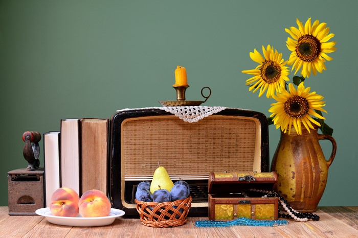 Still life with vintage radio, fruit, books, and sunflowers