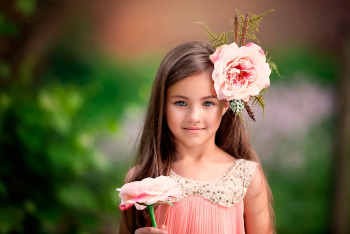 Young girl with flower in hair holding a flower