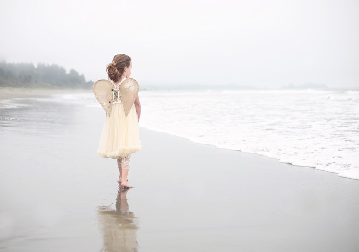Little girl with angel wings on a beach