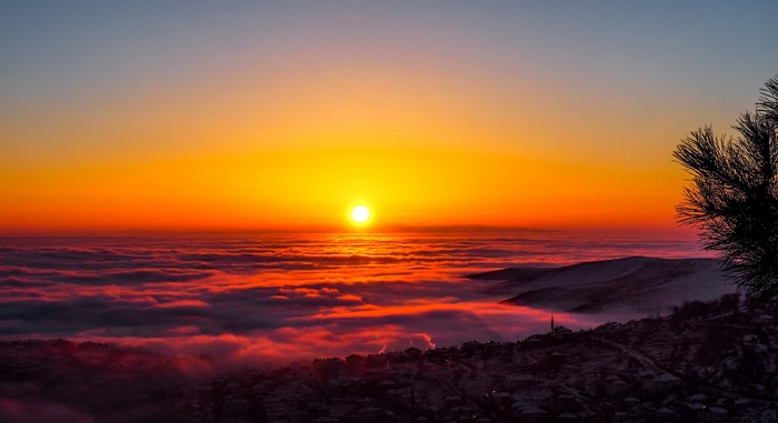 Sunset over clouds with mountains and village