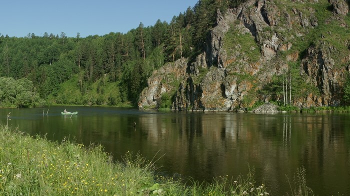 River flowing past a rocky cliff and forest in Siberia