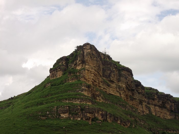 Rocky mountain with green grass and clouds