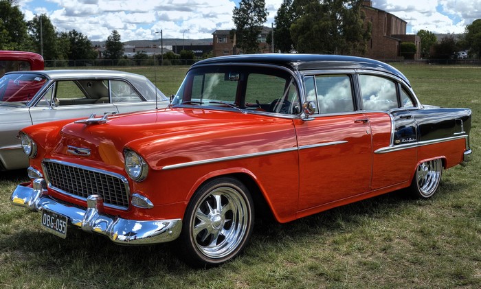 Orange and black Chevrolet Bel Air parked on grass
