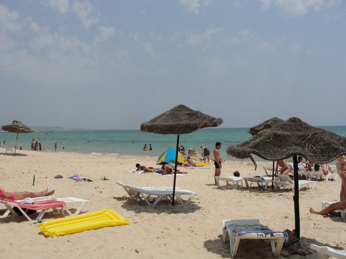 Beach umbrellas and people relaxing on the sand in Hammamet, Tunisia