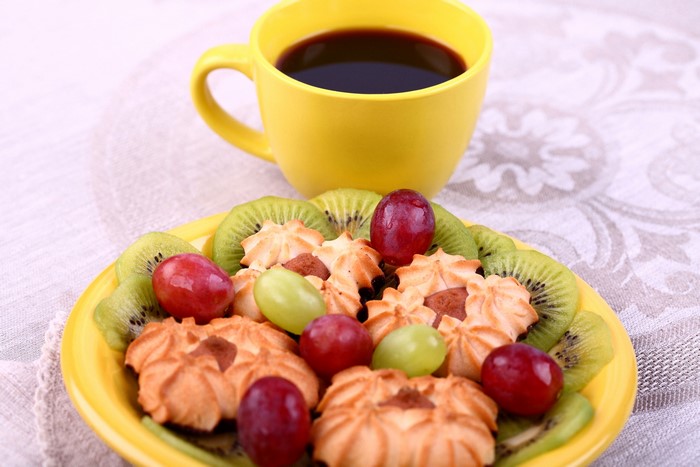 Coffee cup with cookies, kiwi, and grapes