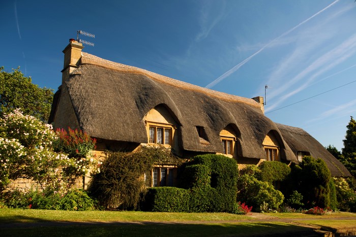 Thatched roof cottage in the United Kingdom with blooming flowers