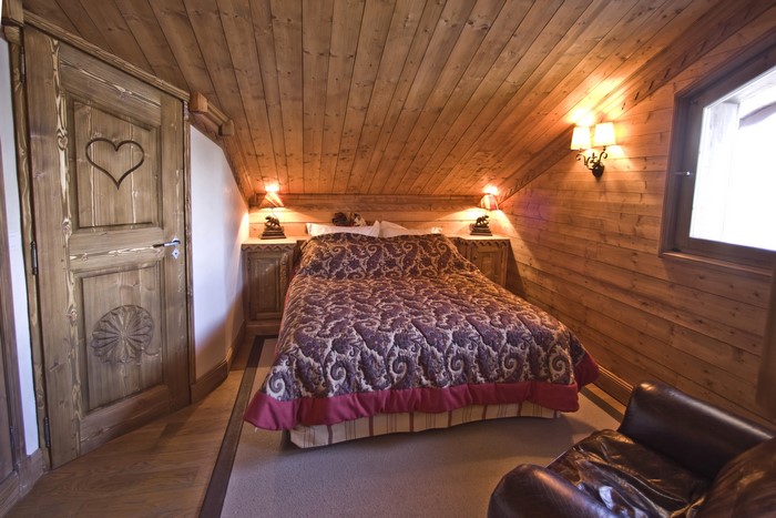 Rustic wooden bedroom with a bed and armchair
