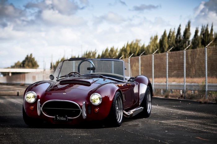 Red AC Cobra convertible parked on asphalt
