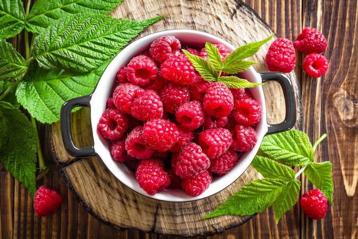 Raspberries in a bowl with leaves