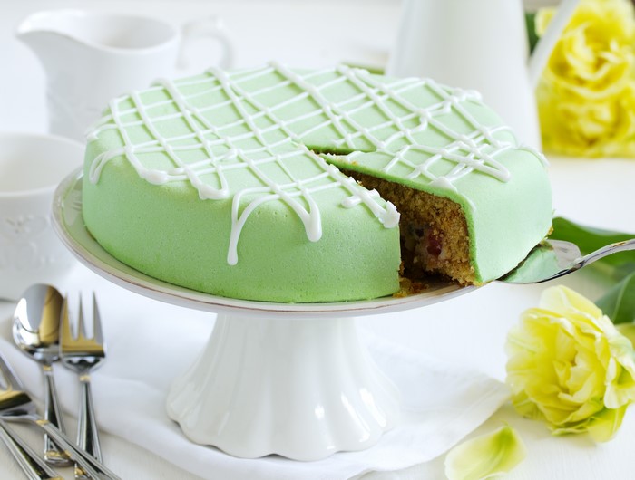 Green cake with white icing on a cake stand