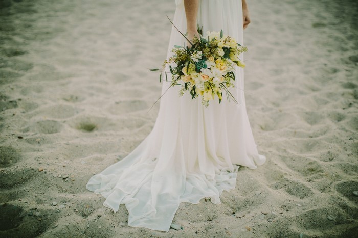 Bride holding a bouquet on a sandy beach