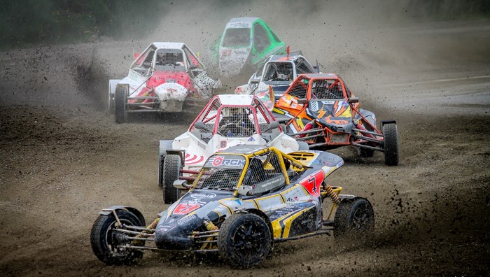 Dirt race with multiple buggies kicking up mud