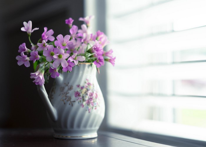 Pink flowers in a decorative vase by the window