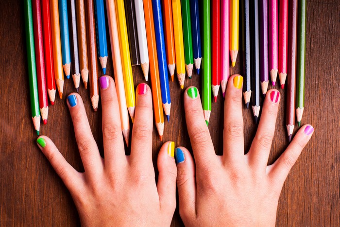 Hands with colorful nails and pencils