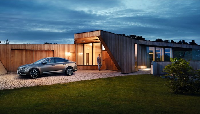 Renault Talisman parked outside a modern wooden house at dusk