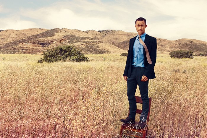 Joseph Gordon-Levitt in a suit standing on a chair in a field