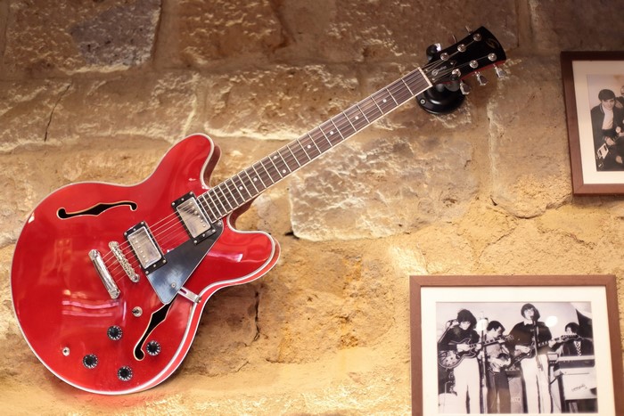 Red electric guitar hanging on a stone wall