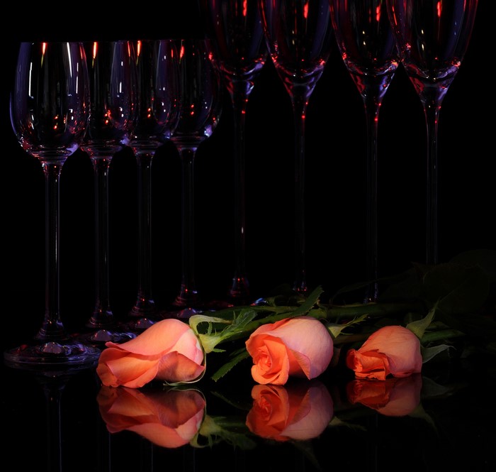 Pink roses and wine glasses on a black background