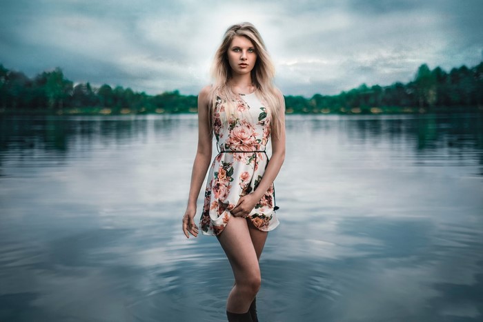 Blonde girl in floral dress standing in a lake