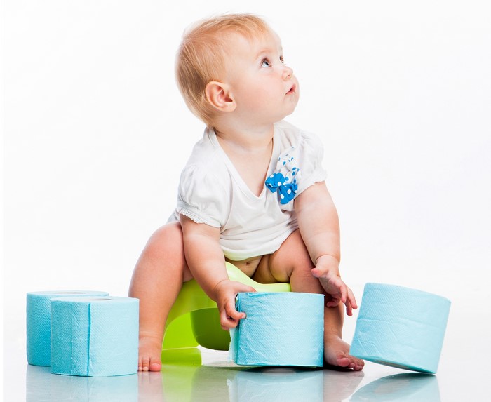 Baby sitting on a potty with toilet paper rolls