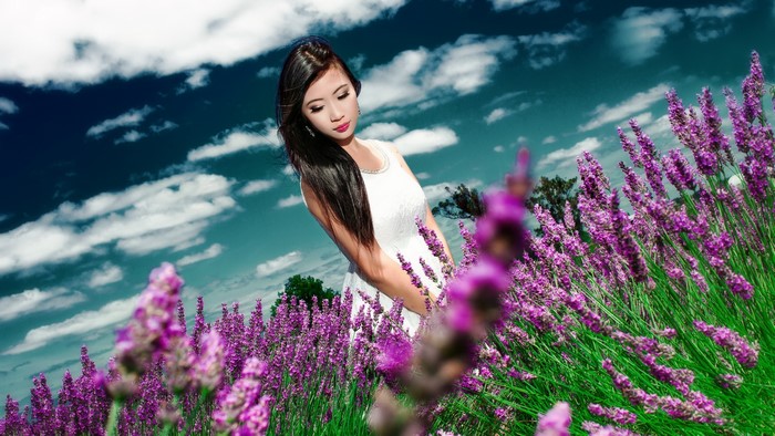 Woman in white dress in lavender field under cloudy sky