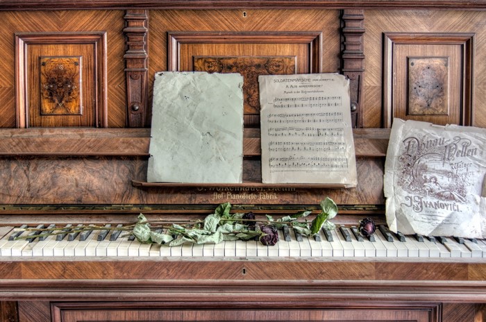 Old piano with sheet music and dried roses