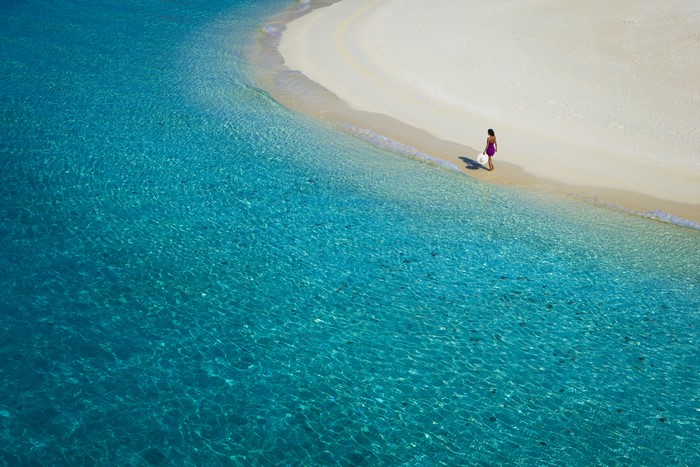Woman walking on a tropical beach with clear blue water