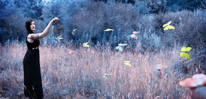 Woman releasing butterflies from a cage in a field