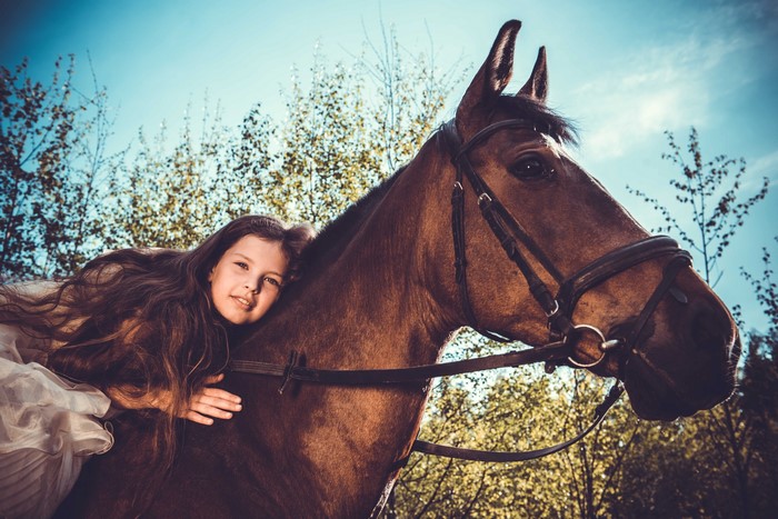 Girl lying on a horse in a forest