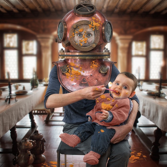 Man in Diving Helmet Feeding a Baby