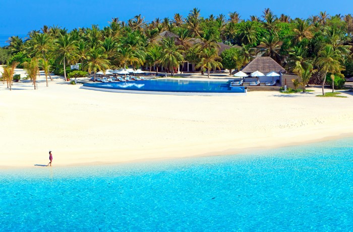 Resort with infinity pool and palm trees on a tropical beach in the Maldives