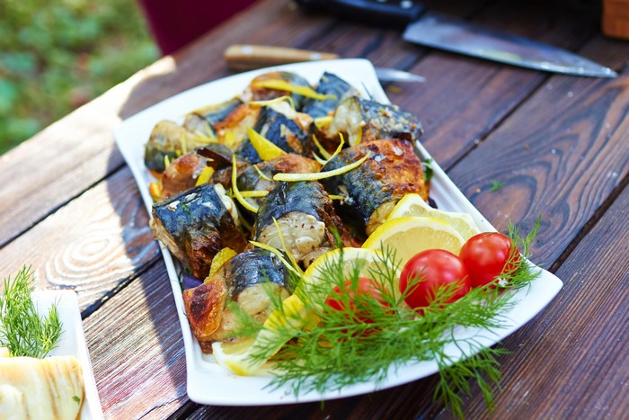 Cooked fish with lemon and tomatoes on a plate
