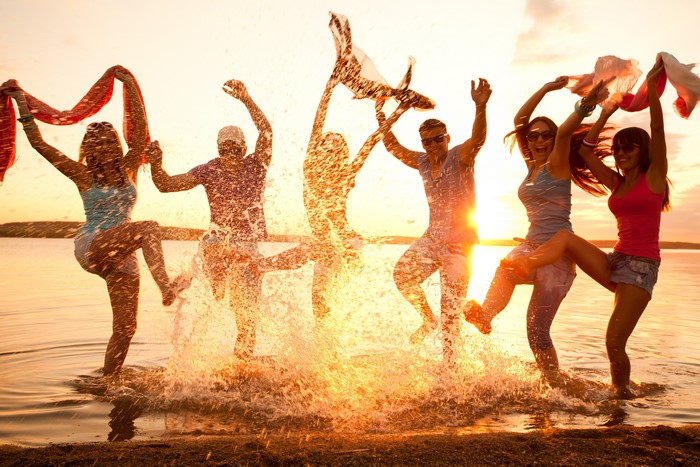 Group of friends splashing in water at sunset