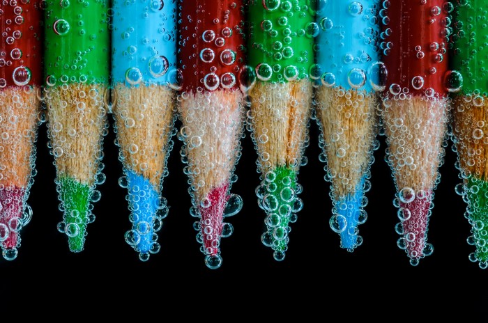 Colored pencils submerged in water with bubbles