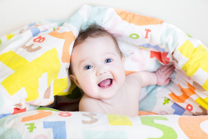 Baby smiling under a colorful blanket