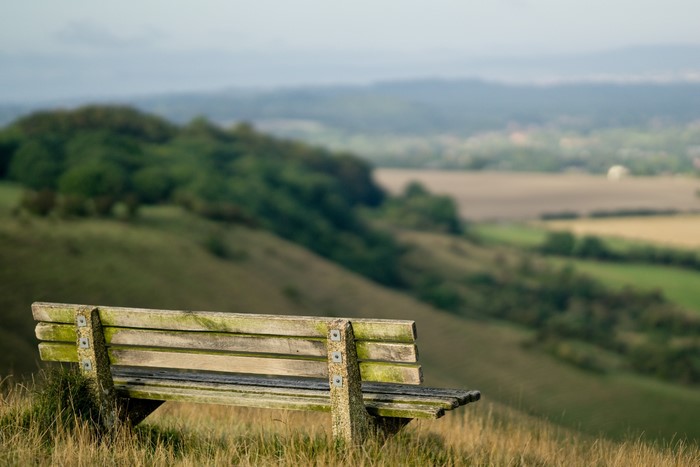 Wooden bench on a grassy hill overlooking a valley