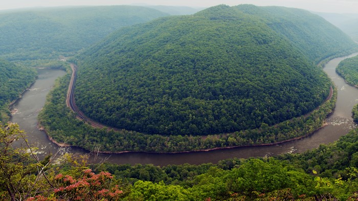 River bend with railroad tracks through a forested mountain landscape