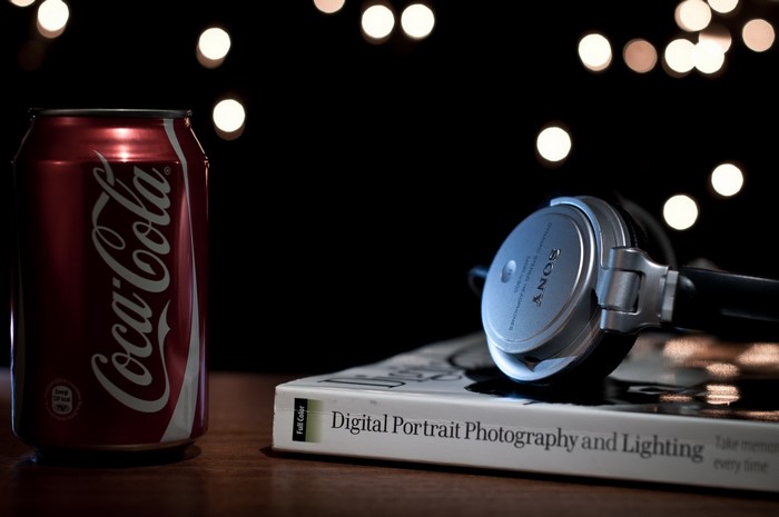 Coca-Cola can with Sony headphones on a book