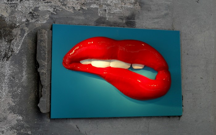 Red lips biting on a teal background