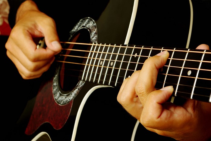 Hands playing an acoustic guitar