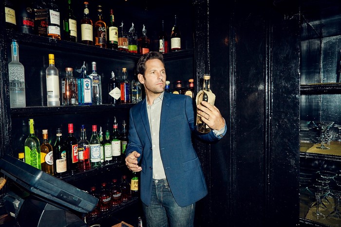 Paul Rudd holding a bottle in a bar