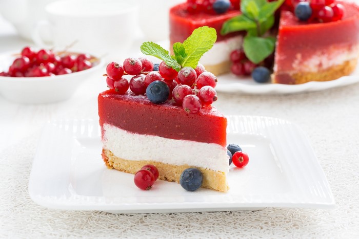 Slice of berry cheesecake with red currants and blueberries
