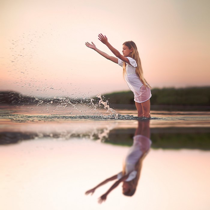 Girl splashing water in a lake at sunset