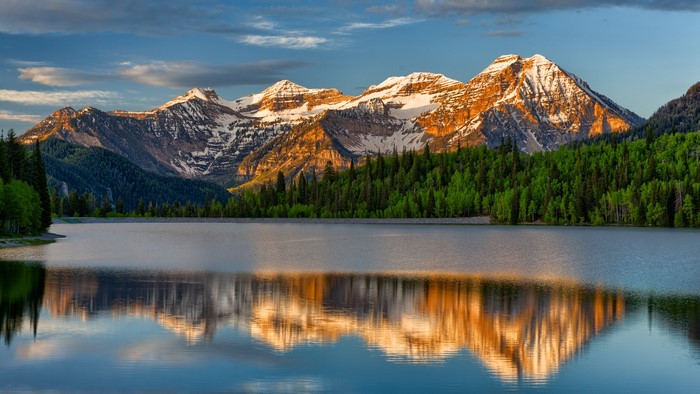 Lake reflecting snow-capped mountains and forest