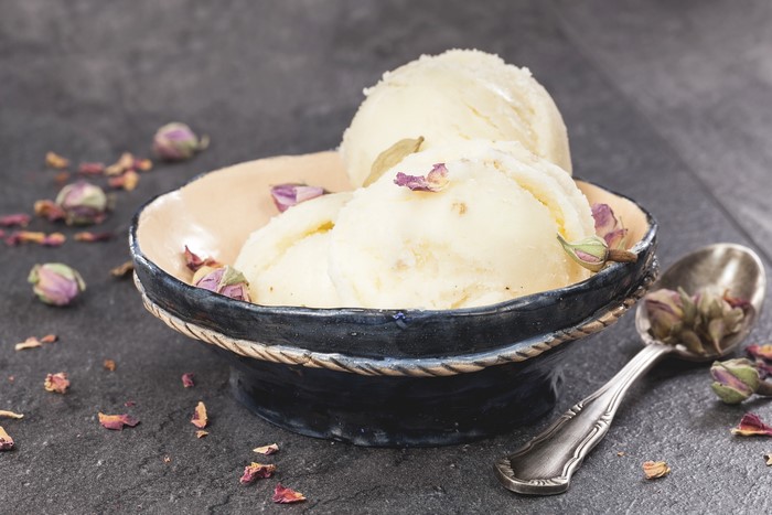 Ice cream in a bowl with rose buds and spoon