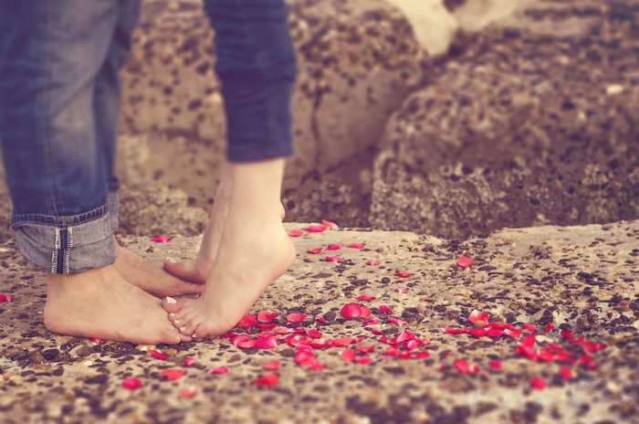 Couple's Legs with Rose Petals on Rocks