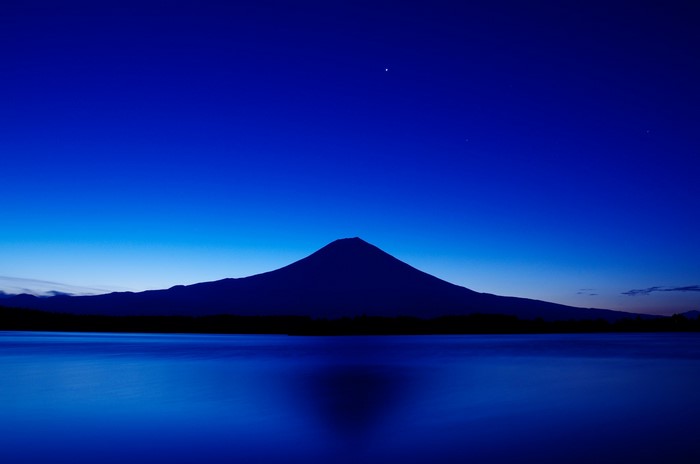 Mount Fuji silhouette over a lake at night