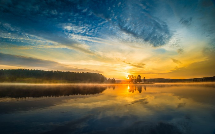 Sunrise over a misty lake with forest