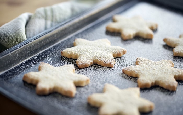 Star-shaped cookies dusted with powdered sugar on a baking sheet